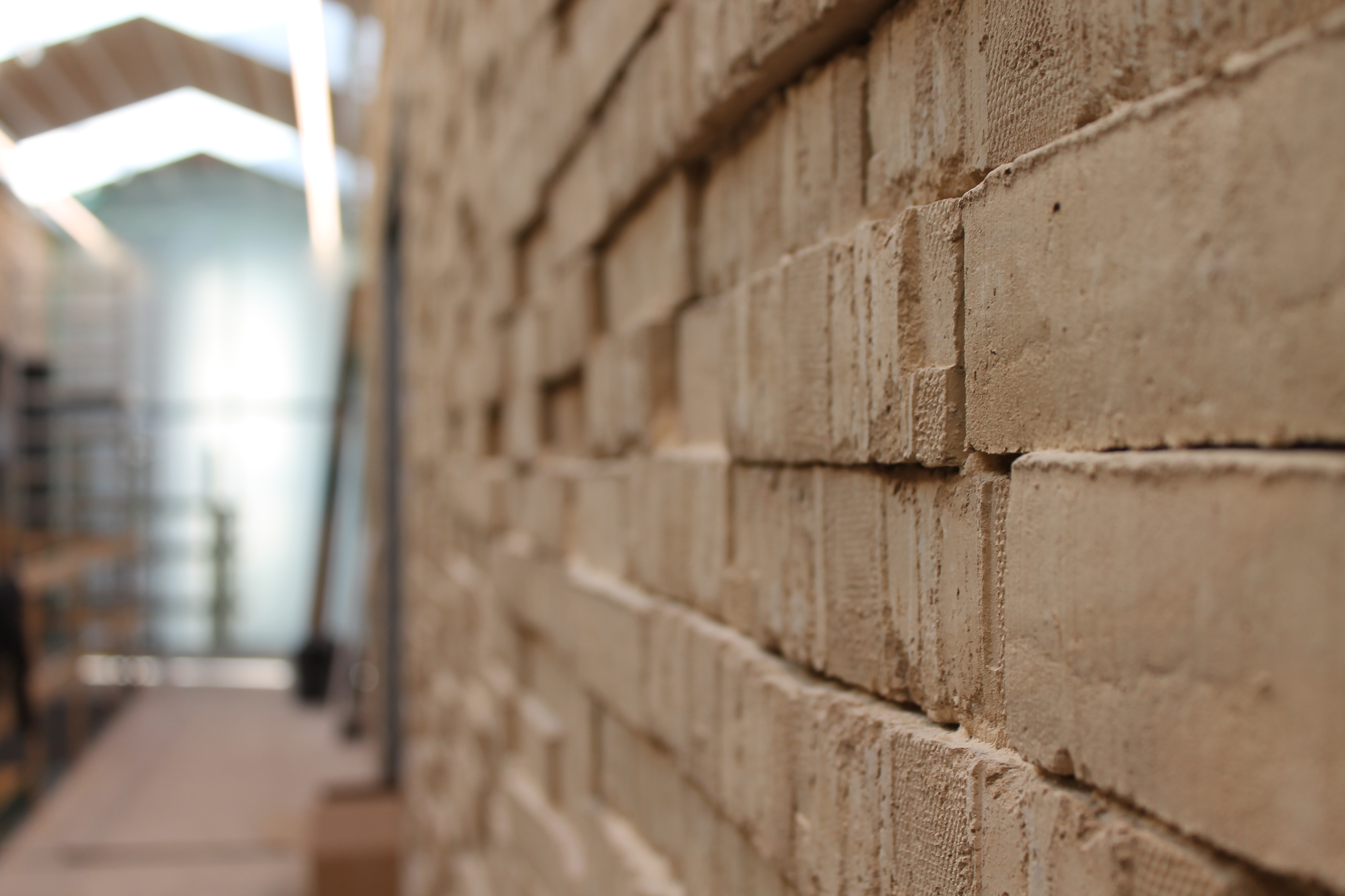 Kaosmuren af gule, rå mursten fungerer både som akustisk dæmper og symbol for samvær med plads til både fællesskab og individualitet. Foto: Askov Højskole