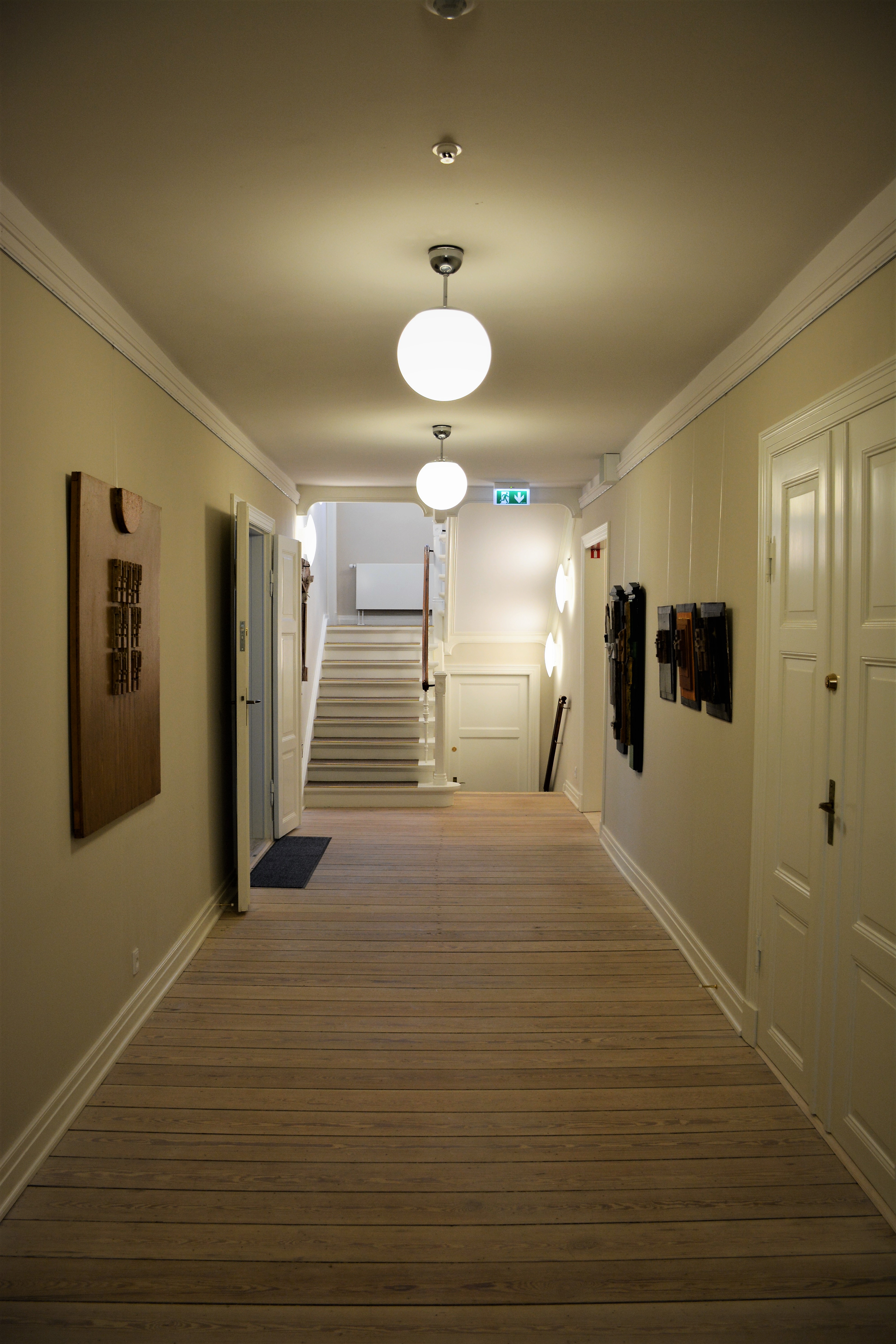 Den brede korridor med smukt restaurerede døre og lokale kunstneres værker på væggen byder velkommen. Foto: C&W arkitekter A/S